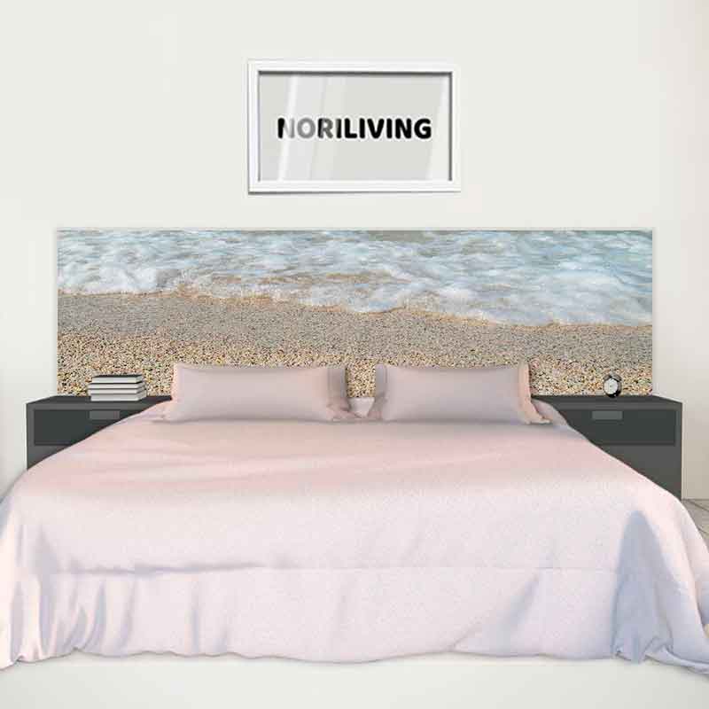 Modernes Schlafzimmer mit Strandbild-Kopfteil Minimalistisches Schlafzimmer mit einem Bett, das ein Kopfteil mit Strand- und Meeresmotiv hat. Über dem Bett hängt ein Bild mit der Aufschrift 'NORILIVING'. Neben dem Bett stehen Nachttische mit Büchern und einer Uhr.