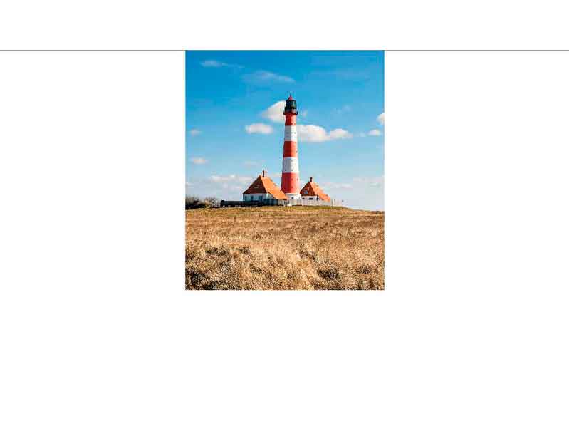 Roter und weißer Leuchtturm steht auf einer Wiese unter blauem Himmel mit einigen Wolken