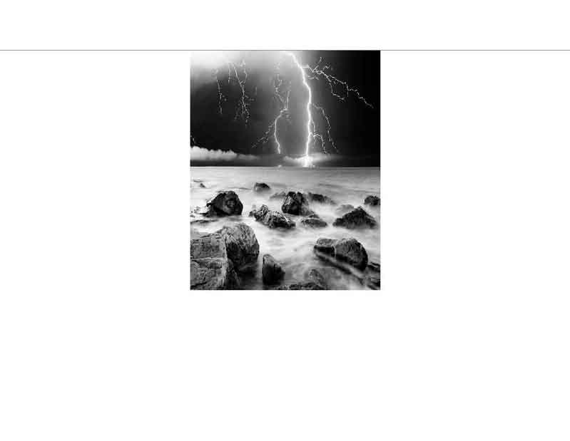 Dramatischer Blitz über felsiger Küstenlandschaft bei Nacht Ein heller Blitz schlägt in einer stürmischen Nacht in das Meer ein, während Wellen an die felsige Küste prallen.