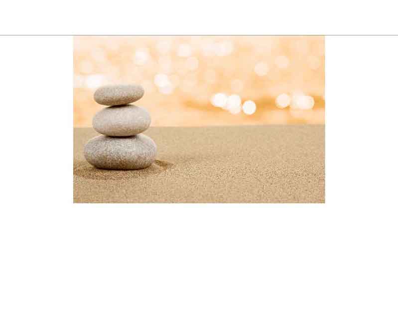 Stapel aus drei flachen Steinen auf Sand, mit einem bokeh Hintergrund in warmen Tönen