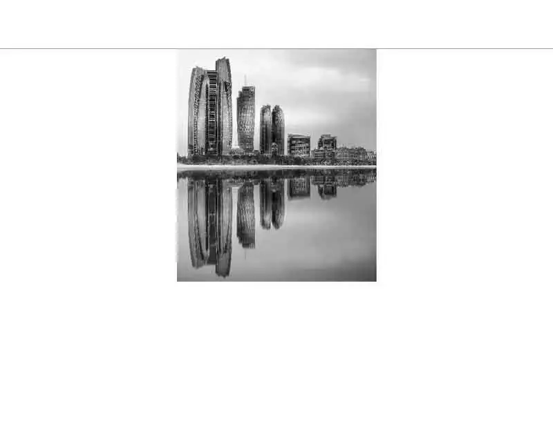 Städtische Skyline moderner Gebäude, die sich im ruhigen Wasser spiegeln, in Schwarz-Weiß.