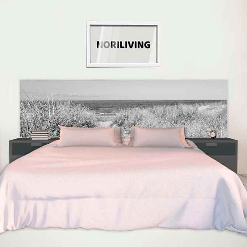 Modernes Schlafzimmer mit großem Bett, beiger Tagesdecke, Fotografie eines Strandes als Betthaupt und Wandbild mit 'NORILIVING' Schriftzug