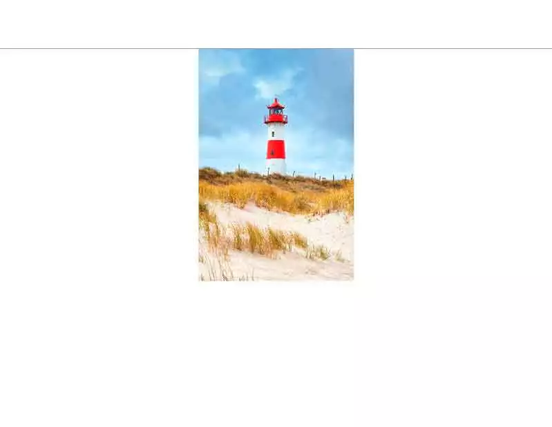 Ein rot-weißer Leuchtturm steht auf sandigen Dünen mit blauem Himmel im Hintergrund, Symbol für maritime Schönheit und Nordsee-Romantik auf Sylt