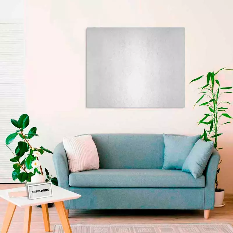 Ein gemütliches Wohnzimmer mit einer blauen Couch, dekorativen Kissen, einem kleinen Tisch mit Pflanze und einem großen Wandbild, umgeben von Zimmerpflanzen.