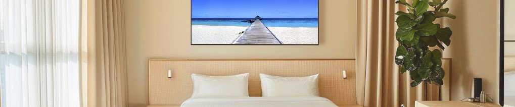 Schlafzimmer mit Doppelbett, Wandbild eines Stegs, Vorhängen und Zimmerpflanze