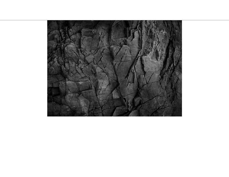 Schwarz-Weiß-Foto einer natürlichen Felsoberfläche mit sichtbaren Rissen und Texturen