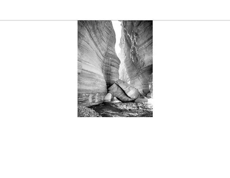 Ein großer Felsbrocken blockiert den schmalen Durchgang in einer beeindruckenden Schlucht.