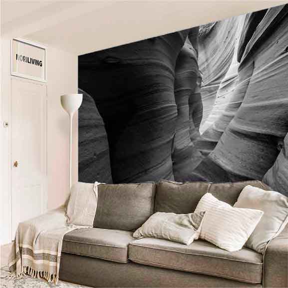 Wohnzimmer mit grauem Sofa und großflächiger Wanddekoration, die einen Canyon darstellt