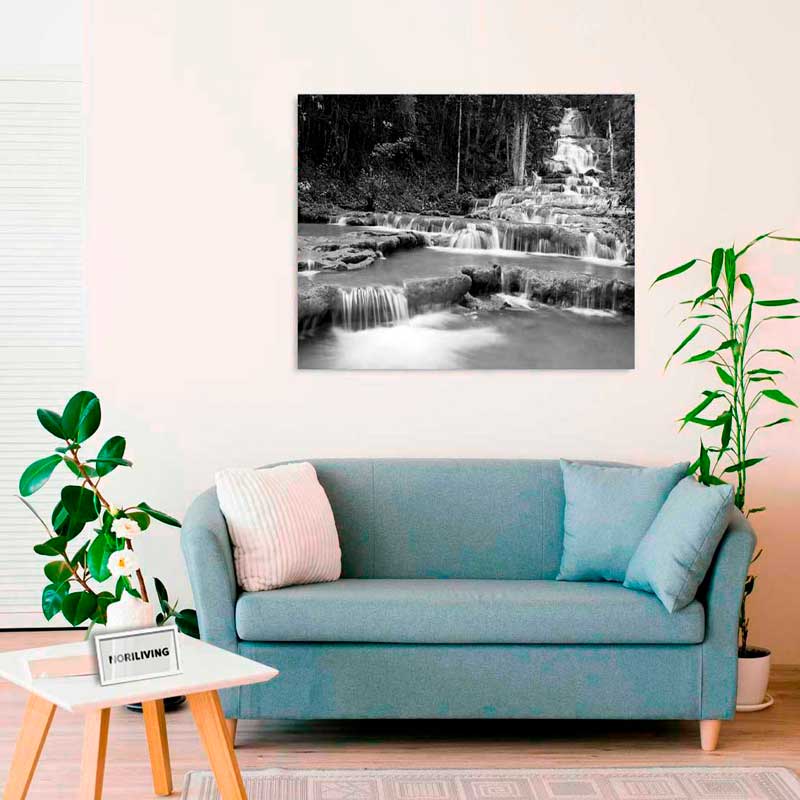 Modernes Wohnzimmer mit blauem Sofa, Kissen, Pflanzen und einem großen Schwarz-Weiß-Wandbild eines Wasserfalls über dem Sofa.