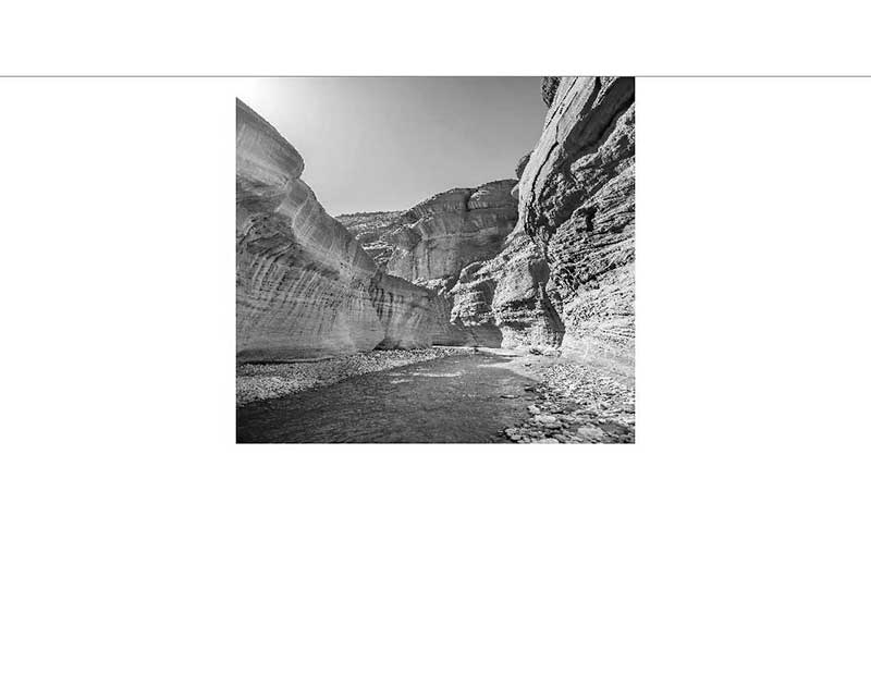 Schwarz-Weiß-Foto einer felsigen Schlucht mit fließendem Wasser inmitten steiler Felswände