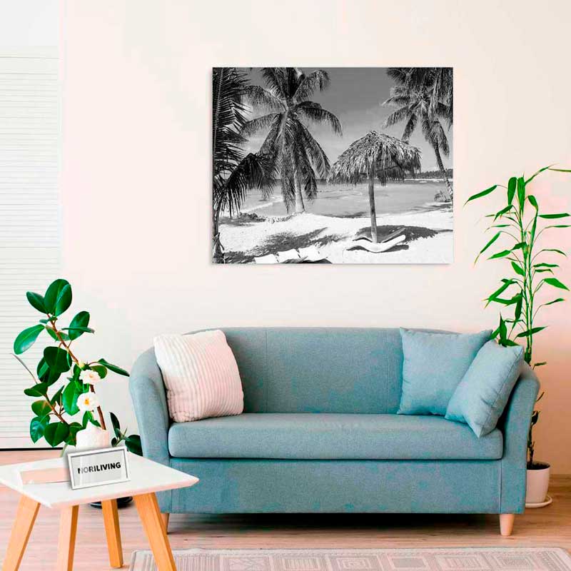 Ein stilvoll eingerichtetes Wohnzimmer mit einem blauen Sofa und einem großen, schwarz-weißen Wandbild von Palmen und Strand.