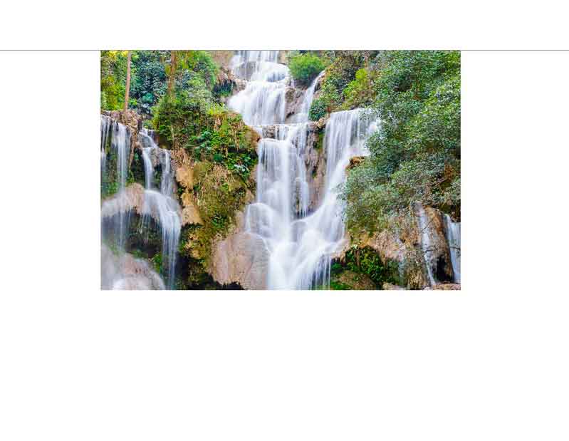 Ein malerischer Wasserfall fließt über Felsen, umgeben von üppigem Grün im Regenwald.