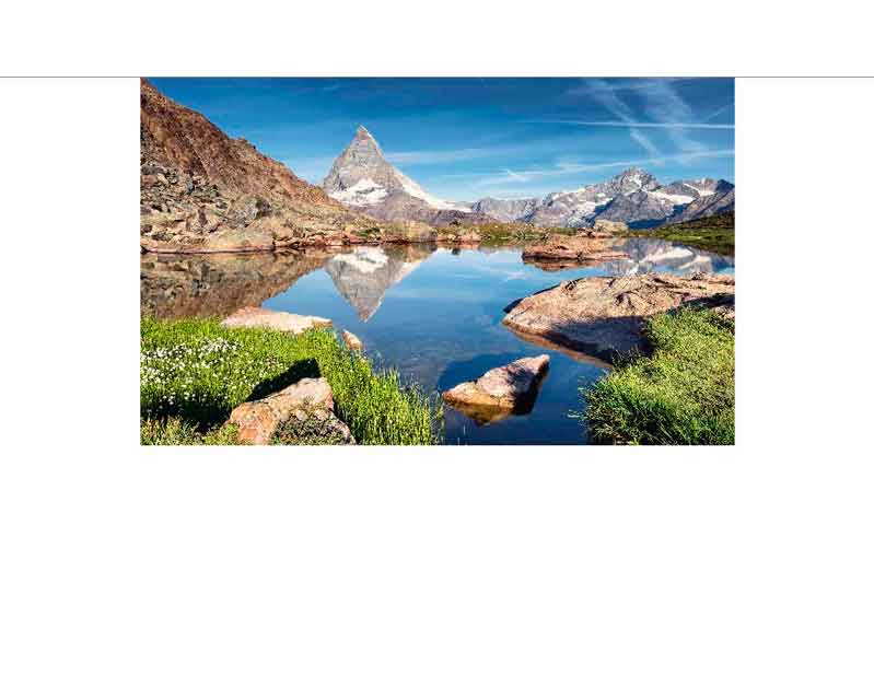 Malebense Landschaft mit Bergsee und Matterhorn im Hintergrund Kristallklarer Bergsee mit dem Matterhorn und umliegenden Bergen, reflektiert im Wasser, umgeben von grünen Wiesen und Felsen, unter blauem Himmel