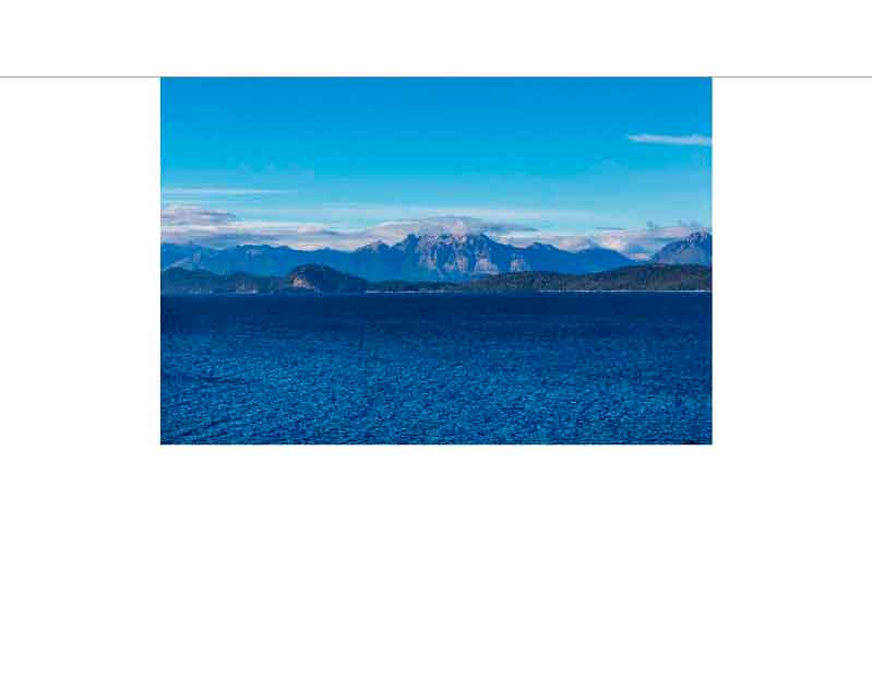 Weitläufige Meeresansicht mit Bergen im Hintergrund unter blauem Himmel