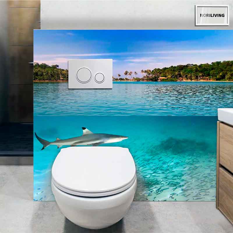 Moderne Toilette vor einer Badezimmerwand mit Fototapete, die eine tropische Insel und einen Hai im klaren Wasser zeigt.