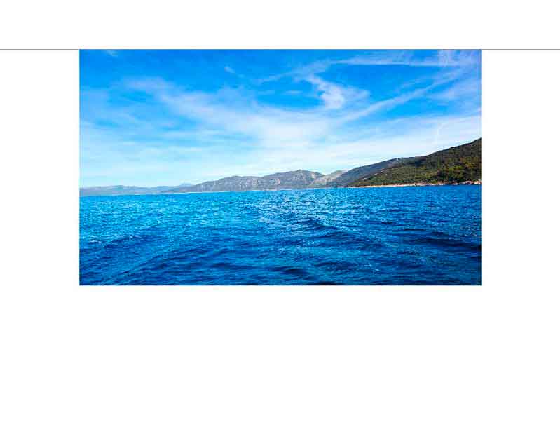 Blaues Meer und bewaldete Berge unter klarem Himmel