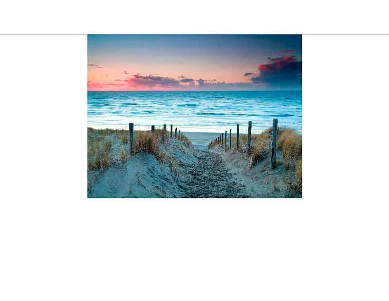Ein sandiger Weg führt durch Dünen zum Meer, während die Sonne den Himmel in leuchtenden Farben erstrahlen lässt.