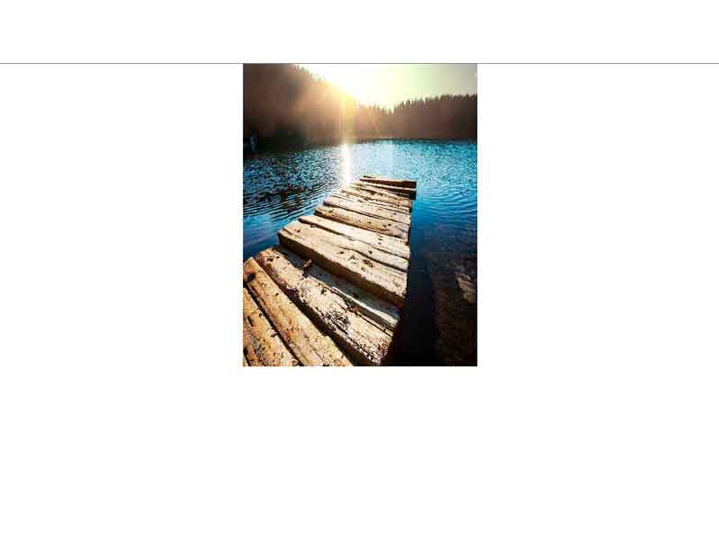 Ein rustikaler Holzsteg, der ins blaue Wasser eines Sees führt, umgeben von bewaldeten Hügeln und Sonnenuntergang.