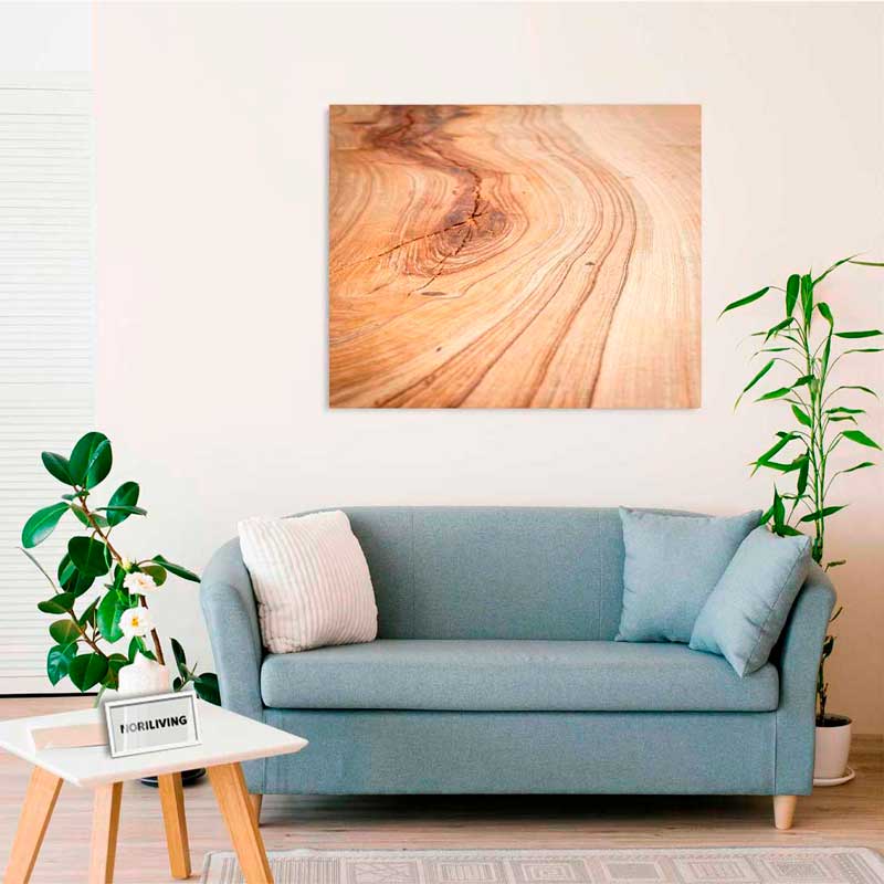 Wohnzimmer mit blauer Couch, Holzwandbild und grünen Zimmerpflanzen