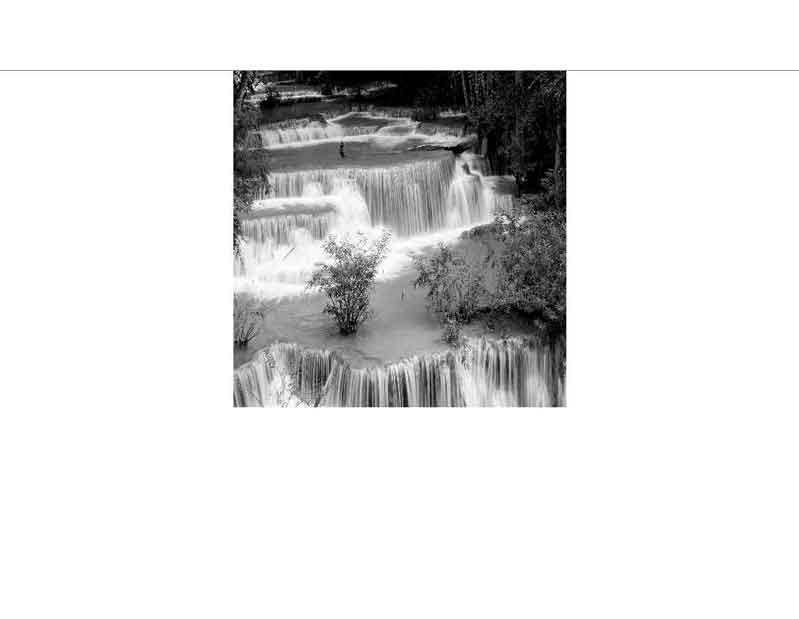 Ein stufenförmiger Wasserfall mit fließendem Wasser und Vegetation in einer schwarz-weißen Darstellung.