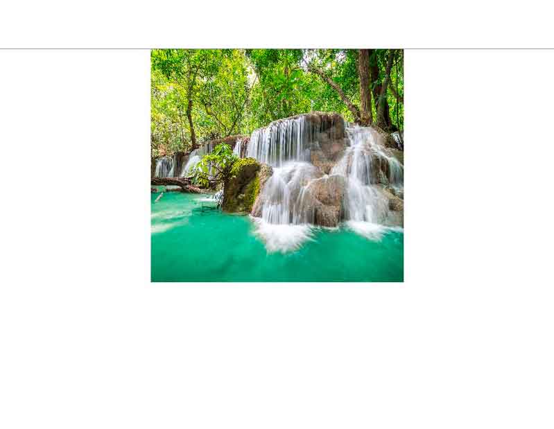 Idyllischer Wasserfall in tropischer Umgebung Ein klarer Wasserfall fließt über Felsen inmitten eines grünen, tropischen Waldes.