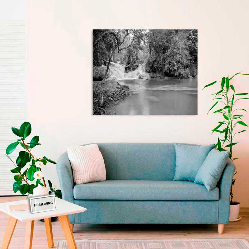 Elegantes Wohnzimmer mit blauem Sofa, Pflanzen und einem großen Kunstwerk an der Wand