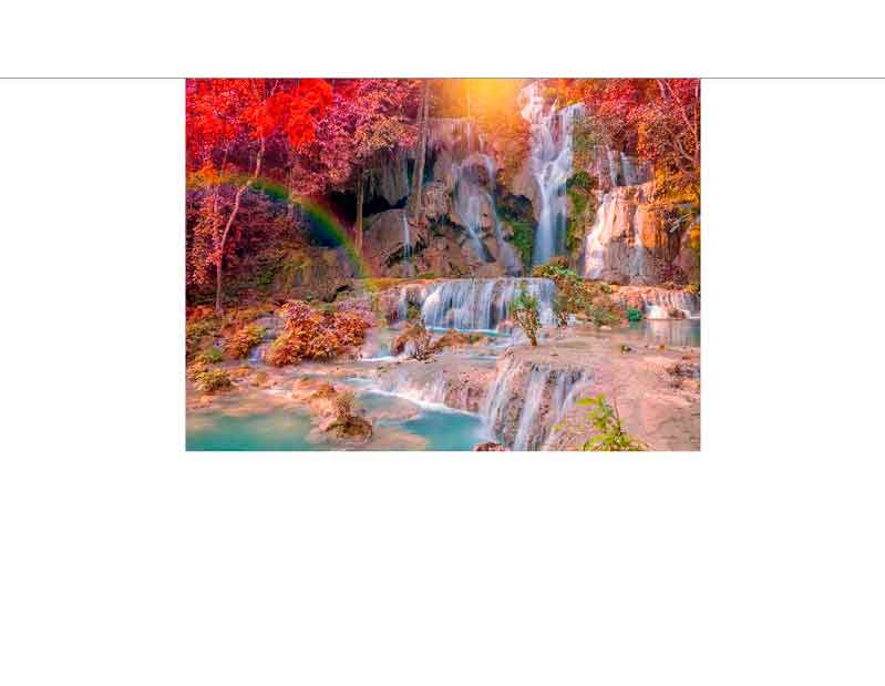 Ein malerischer Wasserfall fließt durch einen herbstlich gefärbten Wald, während ein Regenbogen im Hintergrund sichtbar ist.