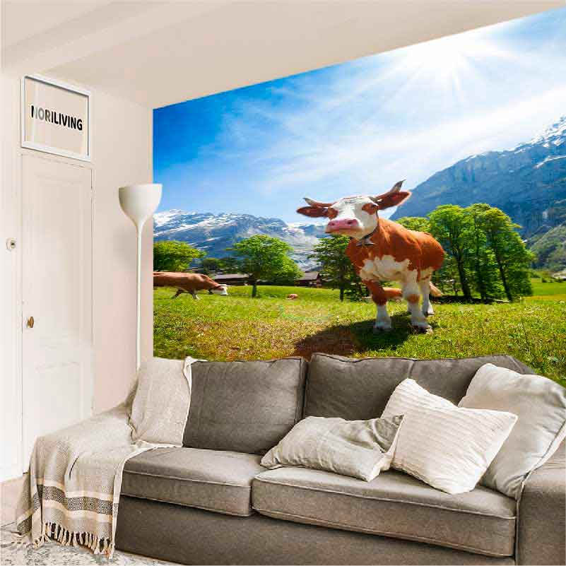 Sofa im Wohnzimmer vor einer großen Fototapete mit einer Kuh auf einer Almwiese und Bergen im Hintergrund