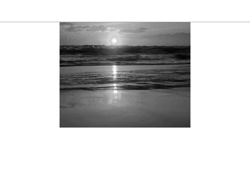 Schwarz-Weiß-Bild eines Sonnenuntergangs am Meer mit reflektiertem Licht auf den Wellen