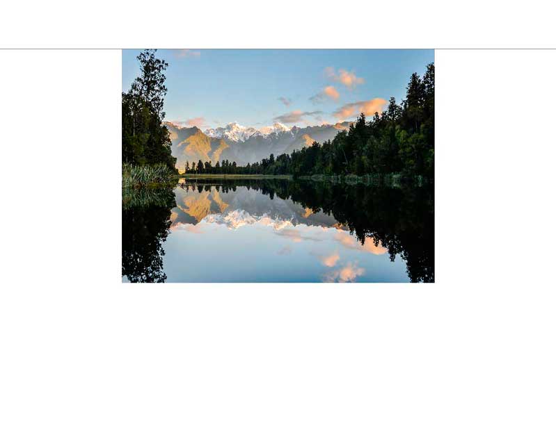 Eine malerische Landschaft mit Bergen, die sich in einem stillen See bei Sonnenuntergang spiegeln, umgeben von üppigen Wäldern.