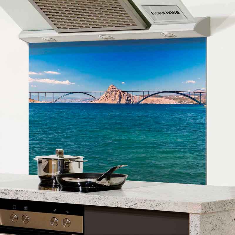 Wunderschöner Küchenspritzschutz mit Brückenmotiv Küchenspritzschutz mit Landschaftsmotiv einer Brücke über einem blauen Meer