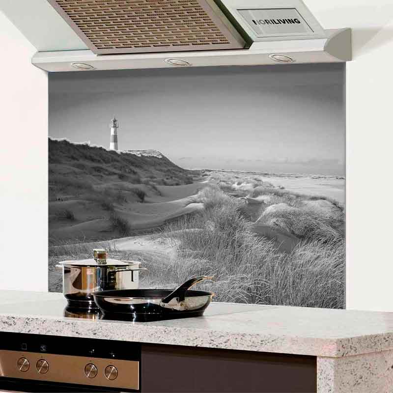 Küchenrückwand zeigt eine Küstenszene mit Dünen und einem Leuchtturm in schwarz-weiß. Im Vordergrund steht eine moderne Küchenausstattung.