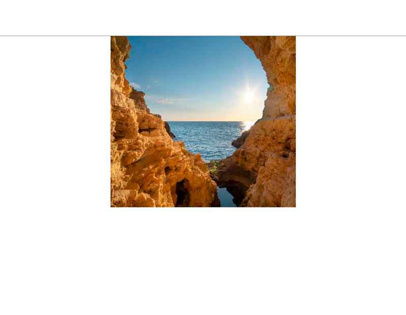 Natürlich geformte Felsen bilden einen Rahmen für den Blick auf das blaue Meer und den Sonnenuntergang am Horizont