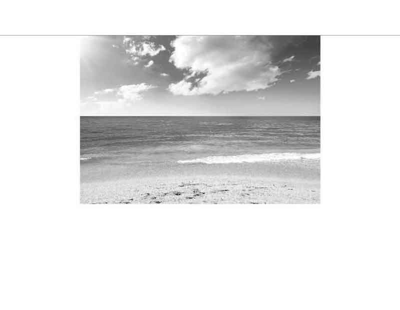 Ruhiger Strand mit Wolken am Horizont Schwarzweiß-Bild eines ruhigen Strandes mit Meerblick und Wolken am Himmel