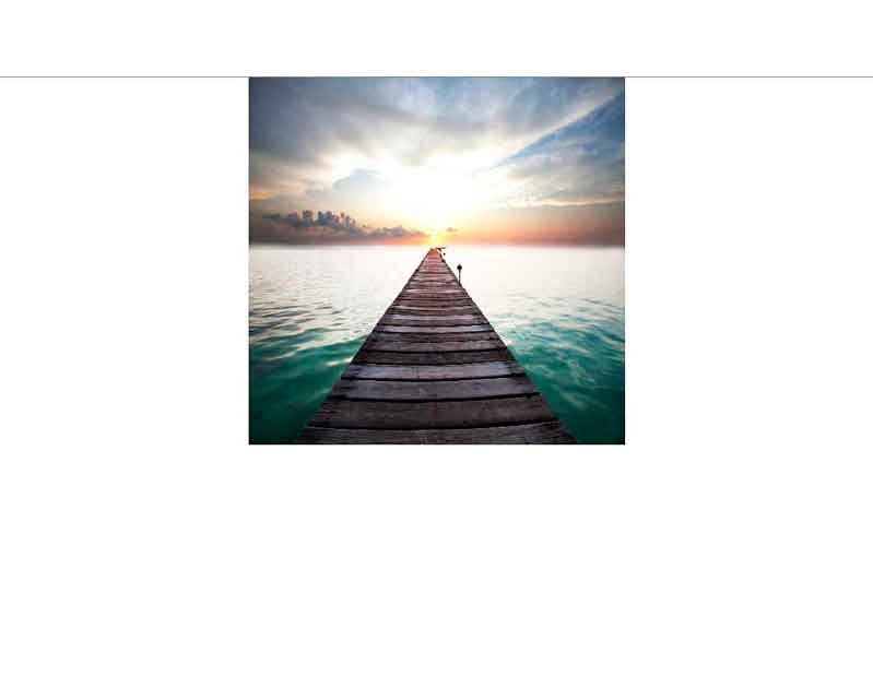 Ein Holzsteg erstreckt sich über ruhiges Wasser in Richtung eines dramatischen Sonnenuntergangs.