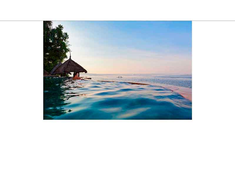 Ein Infinity-Pool mit Blick auf das Meer und einen Sonnenuntergang, umgeben von tropischer Vegetation und einem Pavillon