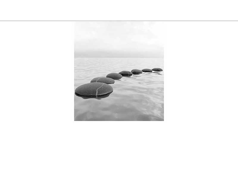 Reihe von glatt geschliffenen Steinen im ruhigen Wasser, minimalistisch in Schwarz-Weiß aufgenommen