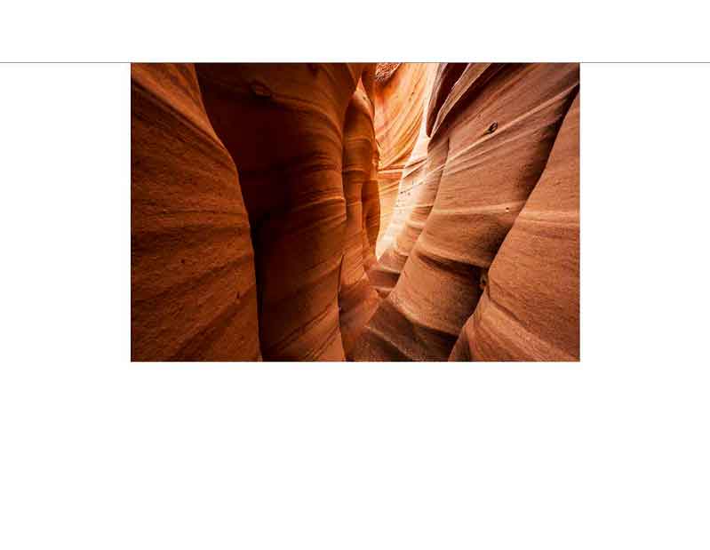 Blick in einen engen Sandsteincanyon mit sanft geschwungenen, rot-orangefarbenen Wänden im Antelope Canyon, Arizona.