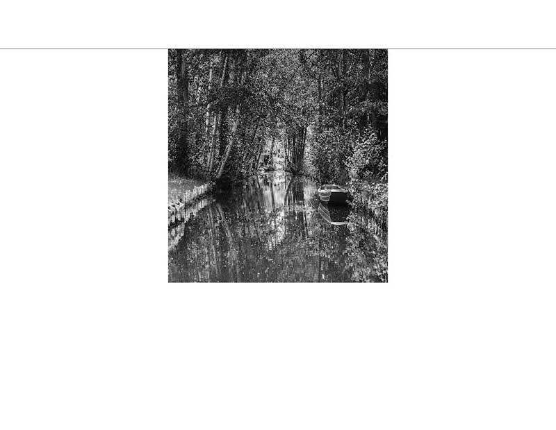 Idyllische Flusslandschaft mit Boot im Wald Schwarz-weiß Foto eines ruhigen Flusses in einem Wald mit einem kleinen Boot am Ufer