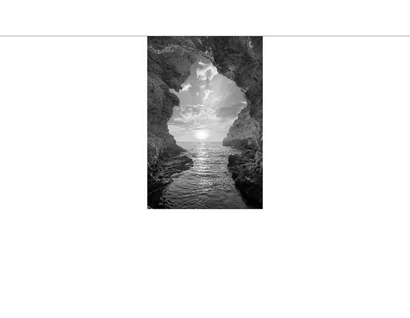 Naturhöhle mit Meerblick bei Sonnenuntergang Schwarz-Weiß-Foto einer natürlichen Höhle, die den Blick auf das Meer und einen malerischen Sonnenuntergang bietet