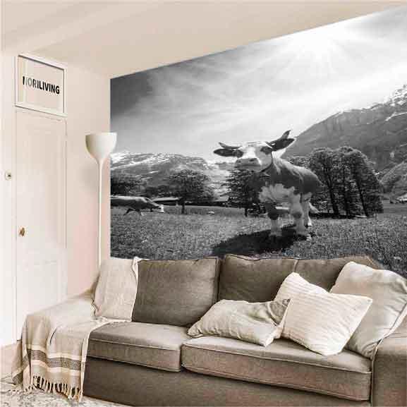 Schwarz-weiß Wandbild mit Kuh und Berglandschaft im Wohnzimmer Ein Wohnzimmer mit einem Sofa, dekoriert mit einem großen schwarz-weiß Wandbild, das eine Kuh in einer Berglandschaft zeigt.