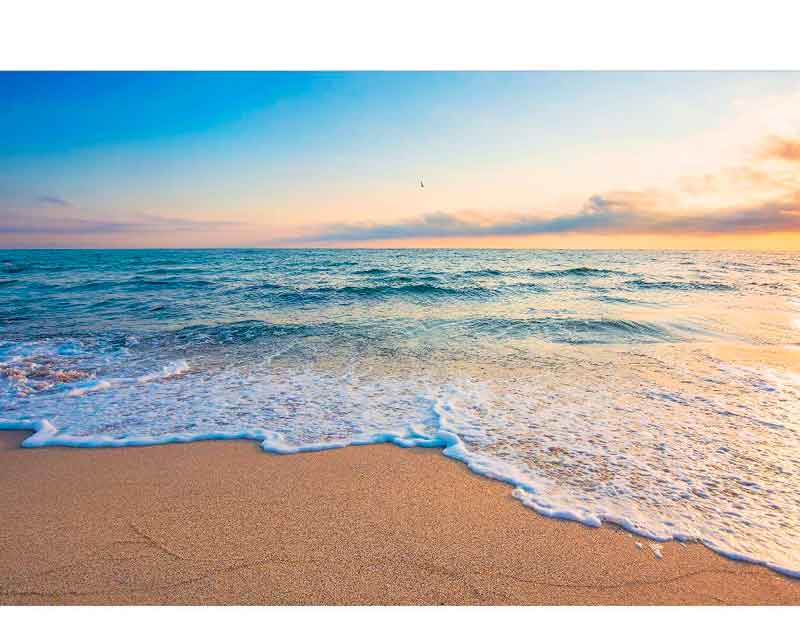Ruhiger Strand bei Sonnenuntergang mit sanften Wellen, die am goldenen Sand brechen