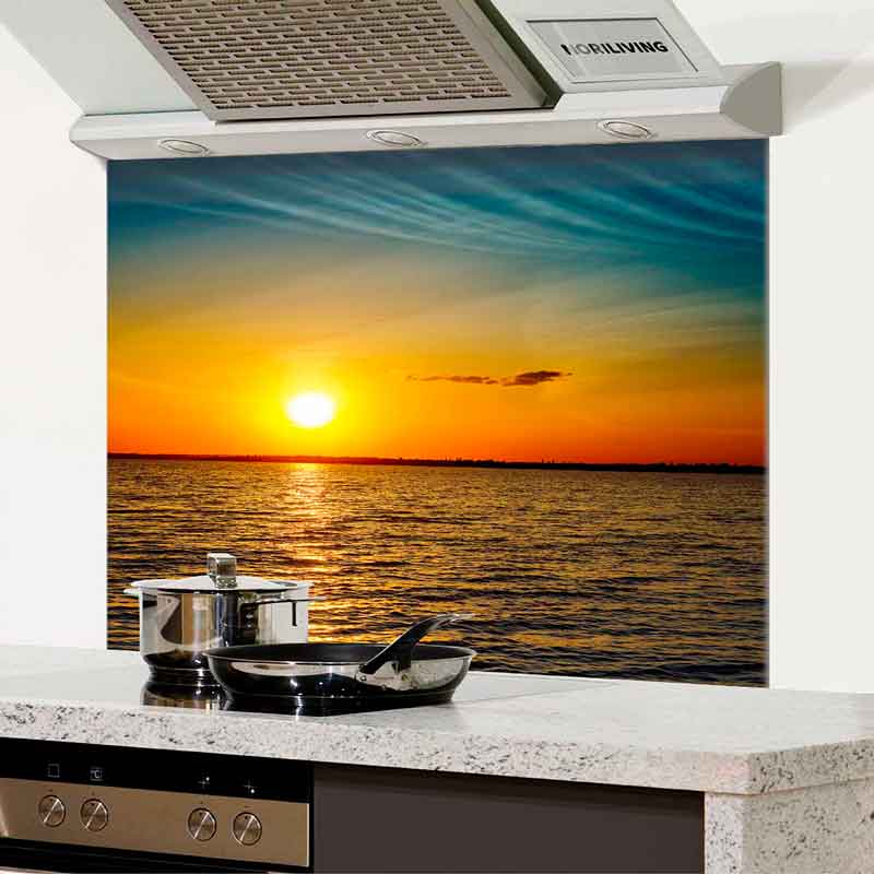 Moderne Küchenrückwand zeigt Sonnenuntergang über dem Meer hinter Herd und Pfannen