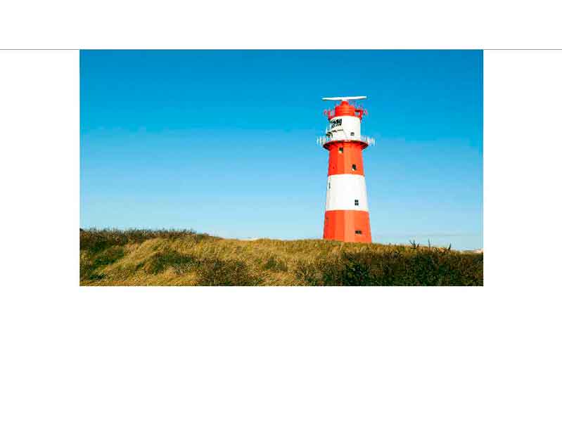 Ein rot-weißer Leuchtturm steht auf einer Wiese unter einem klaren blauen Himmel.