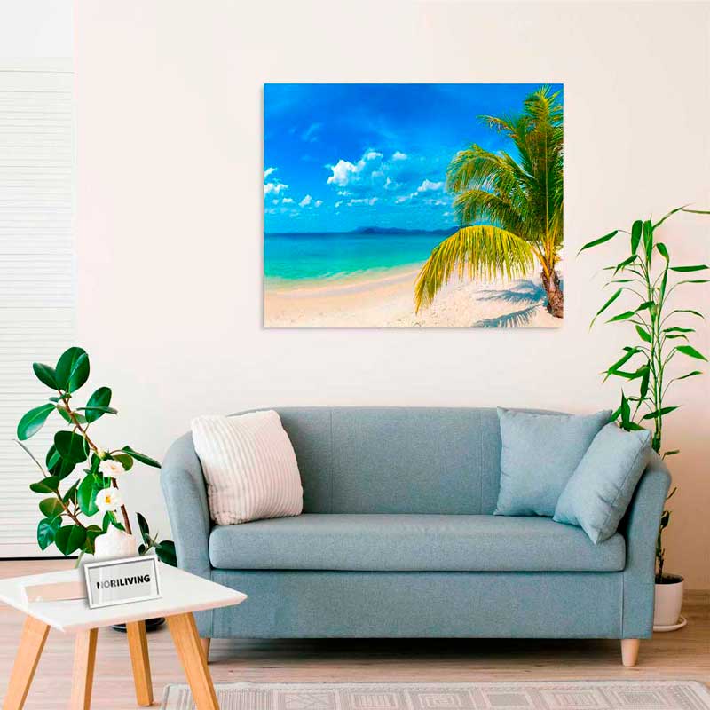 Ein stilvolles Wohnzimmer mit einem Sofa, Pflanzen und einem Leinwandbild von einem Strand mit Palmen und türkisfarbenem Meer.