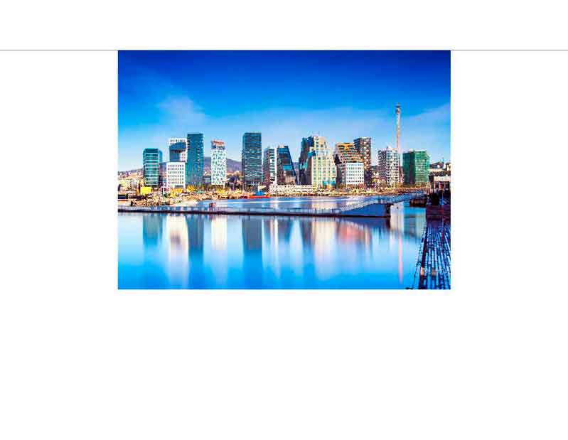 Panoramablick auf die moderne Skyline einer Hafenstadt mit reflektierenden Wolkenkratzern im Wasser unter klarem blauem Himmel